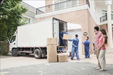 couple supervising movers unloading boxes from a truck