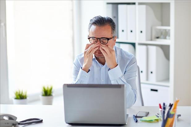 Dissapointed man sitting at desk after not getting raise