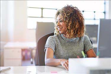 smiling employee looking to the side while working on her laptop