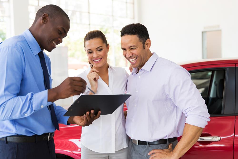 car salesperson going over details with his clients