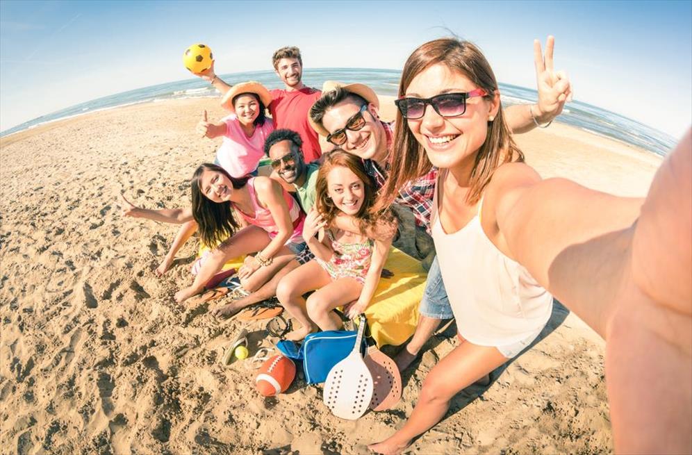 Fun group of people out on vacation while taking selfies that cause others back home to feel left out.