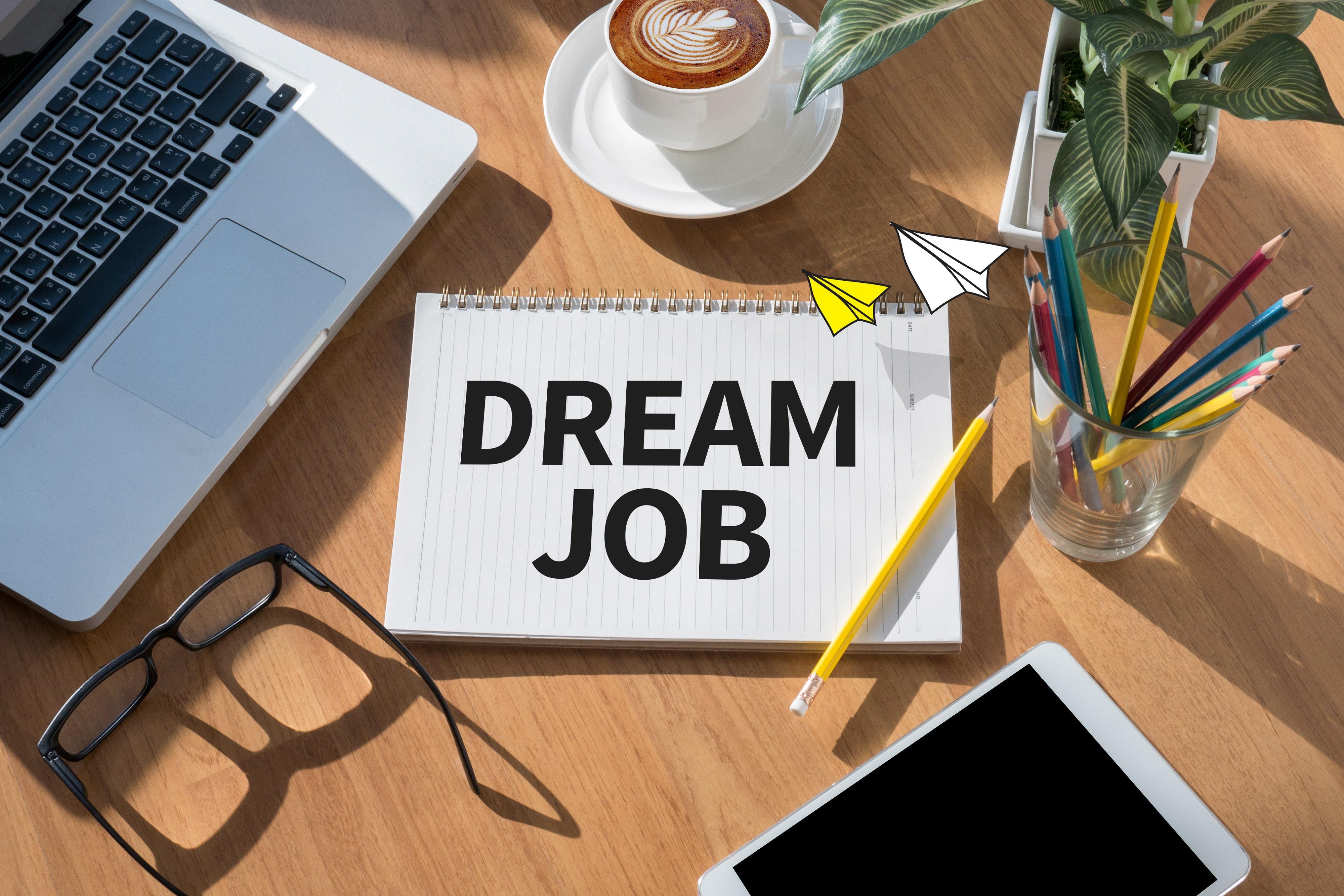 desk with the words "dream job" on a notebook