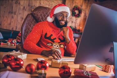 job seeker searching for work online wearing a christmas sweater and hat