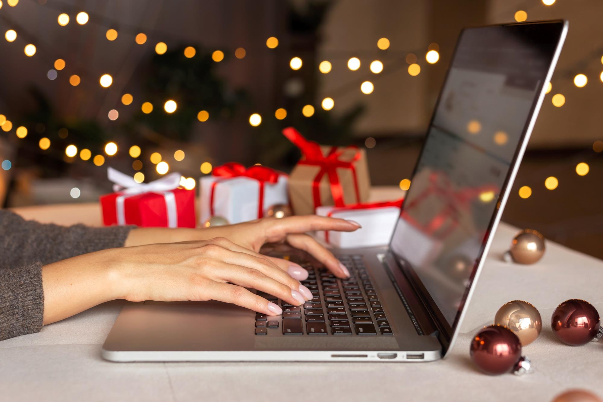 close up of hands typing on a laptop with holiday decorations on the table