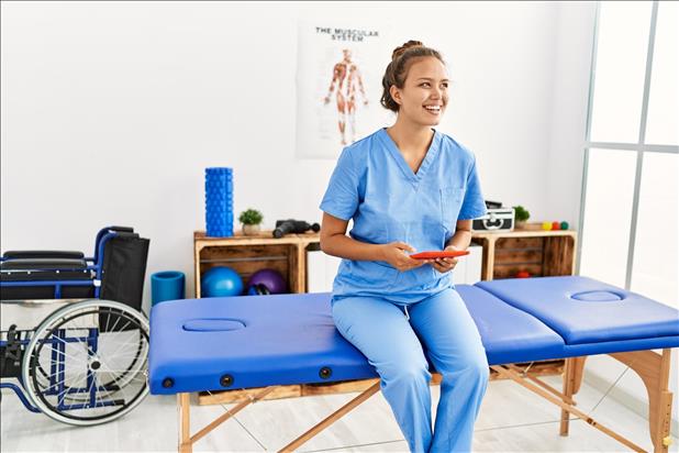 smiling physical therapist sitting on her table