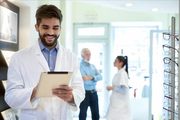 happy optometrist at his practice with team members in the background