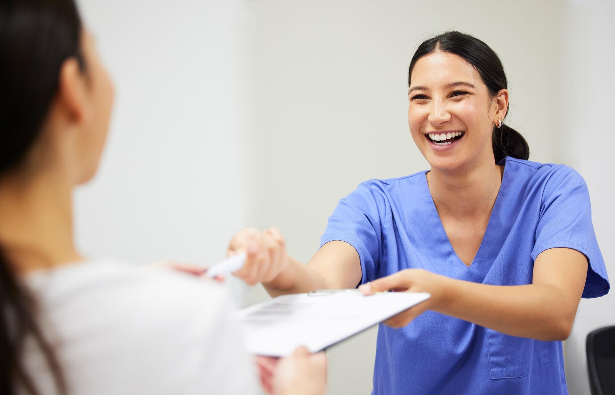 smiling healthcare team member handing someone a clipboard
