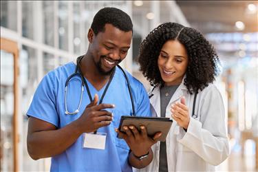 two smiling healthcare team members looking at a tablet