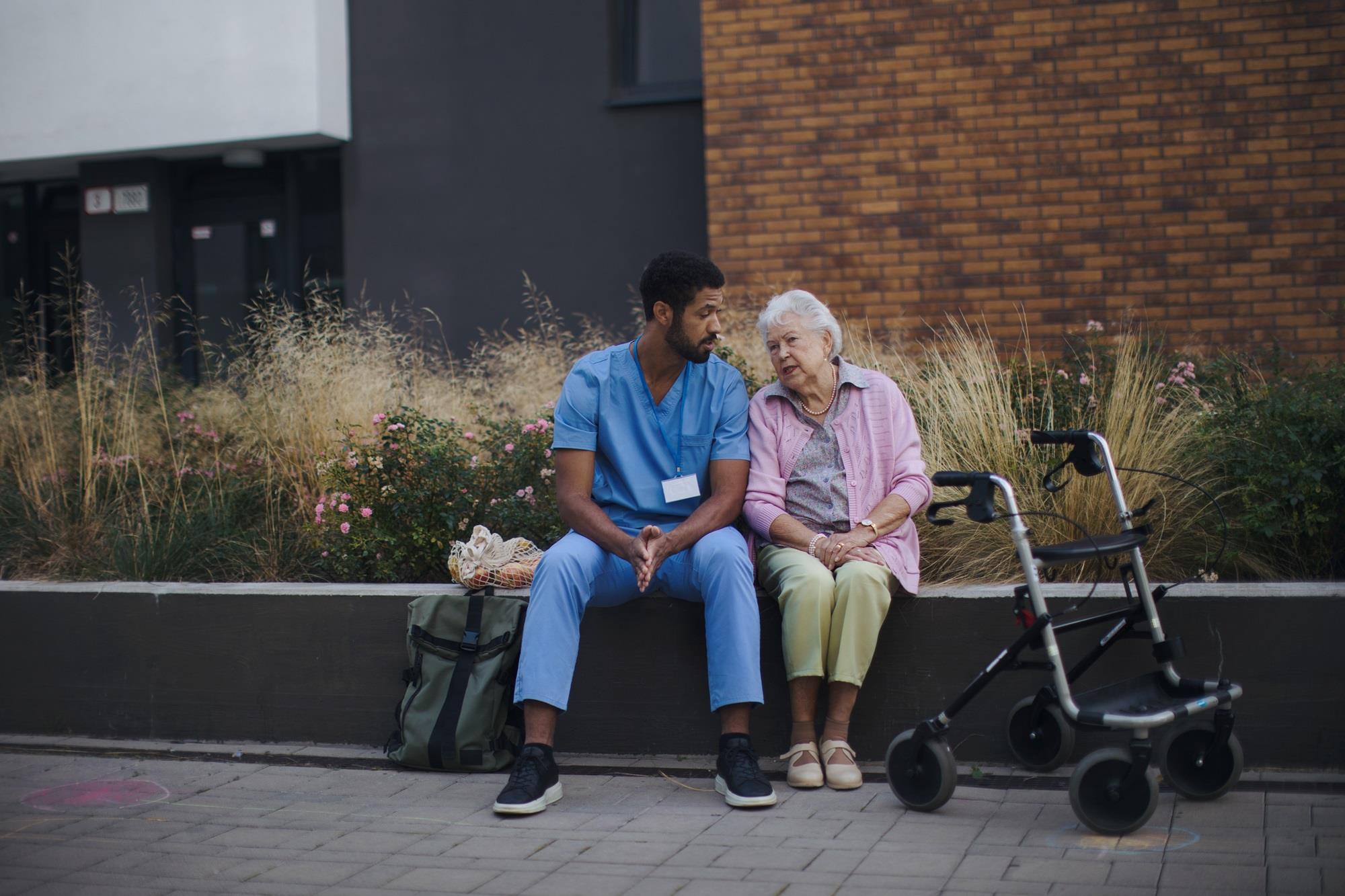 nurse sitting outside with a resident at a nursing home