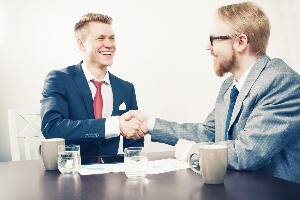 sales professional closing a deal with a client and shaking his hand