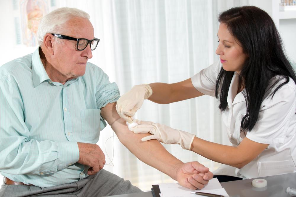 phlebotomist drawing blood from an elderly patient