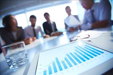 close up of a financial chart with finance professionals meeting in the background