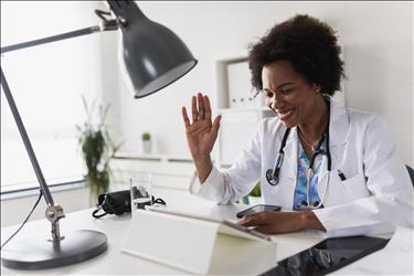 telemedicine doctor waving hello to her patient on her computer