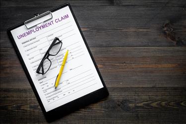 unemployment claim form on a table with a pen and a pair of glasses