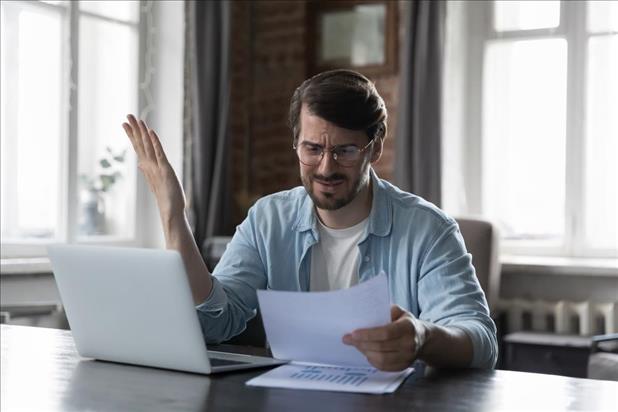 man at his desk looking disappointed at a piece of paper