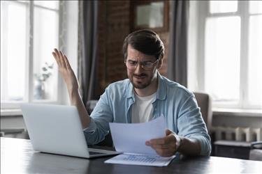 man at his desk looking disappointed at a piece of paper