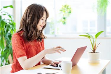 woman looking at a laptop while working from home