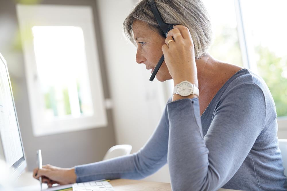 inside sales professional working at her computer and talking on the phone via a headset