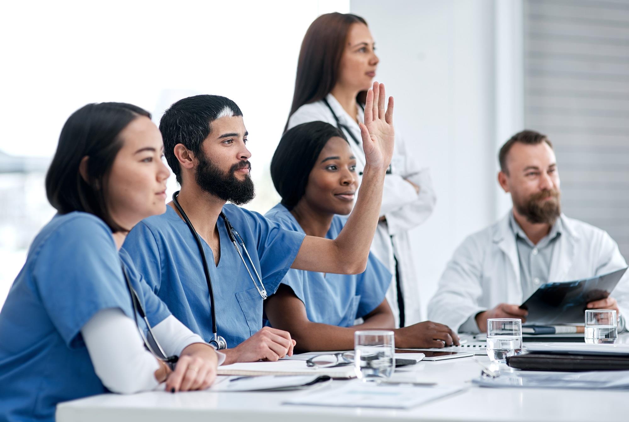 nurse raising his hand during a medical team meeting