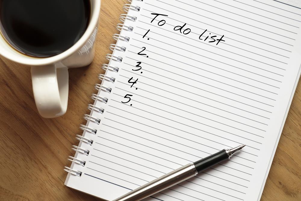 To-do list waiting to be filled out next to a cup of coffee