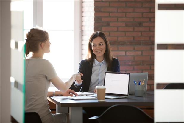 Two women smiling and shaking hands after negotiation