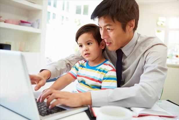 Working father with his son in his lap in front of a computer