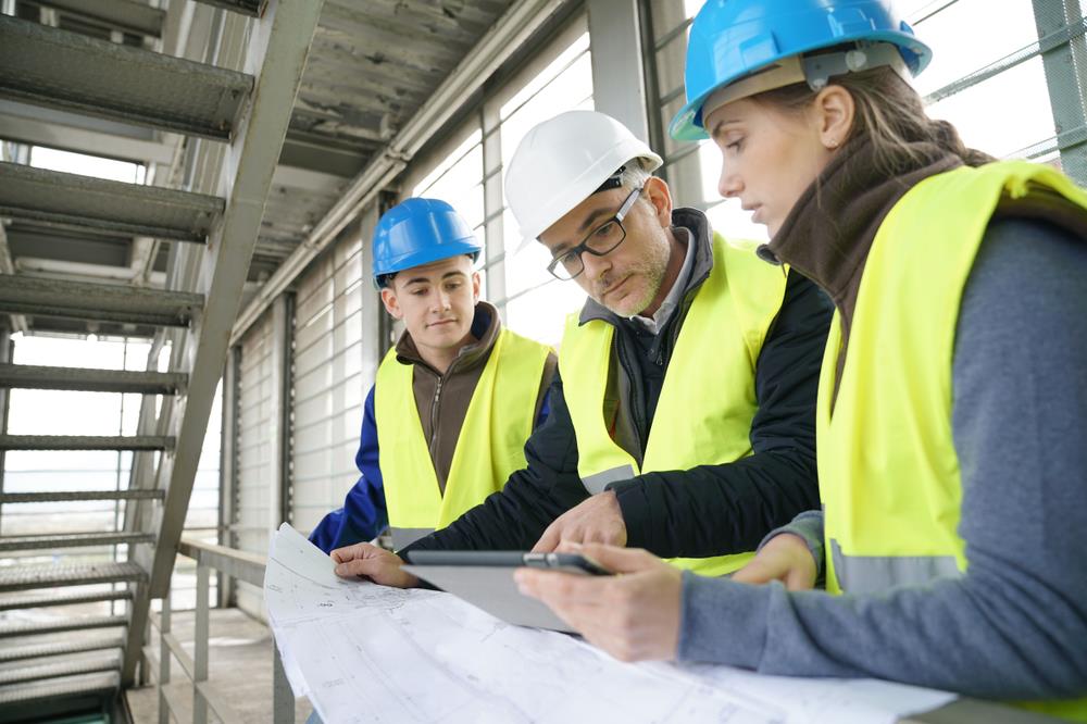 three construction team members reviewing building plans