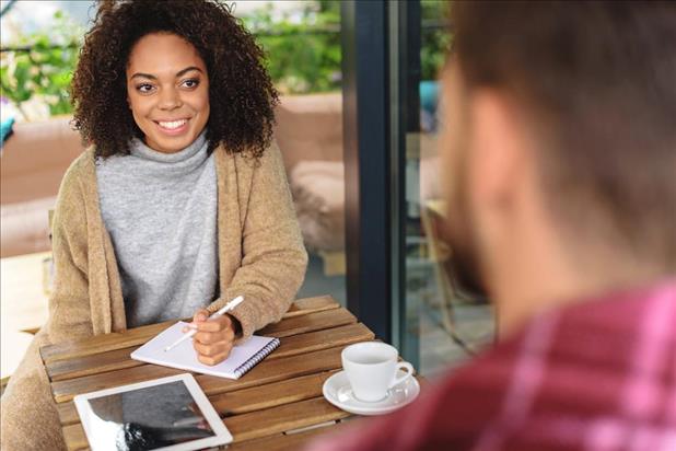 Woman taking notes during informational interview at cafe