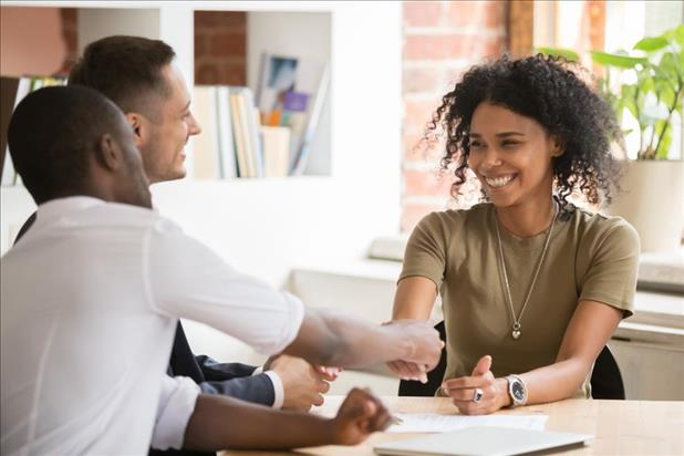 Woman shaking hands with two smiling people in job interview