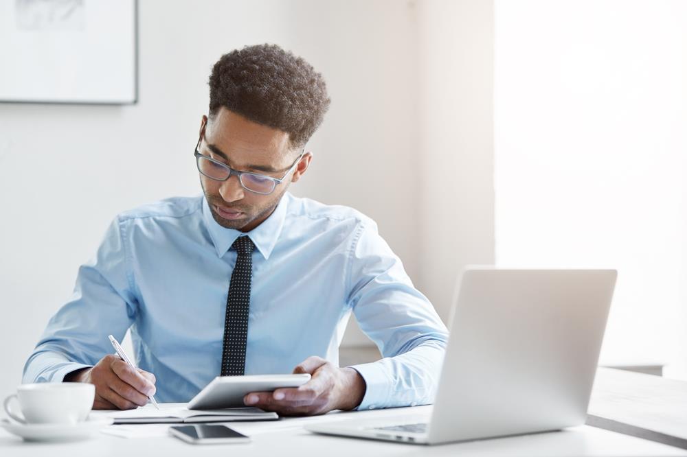 lawyer taking notes while working on his laptop