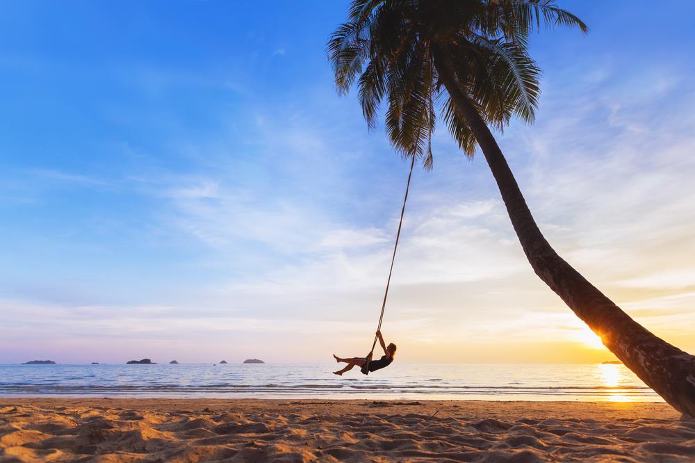 Young woman on a swing at the beach