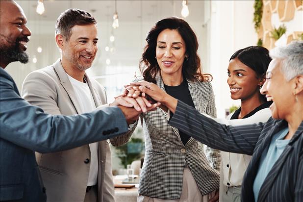 group of multi-generational employees putting their hands together
