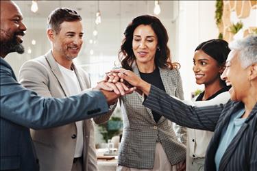 group of multi-generational employees putting their hands together