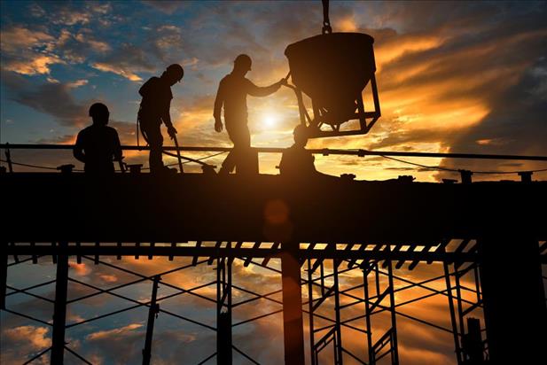 construction team working on site with a sunset in background