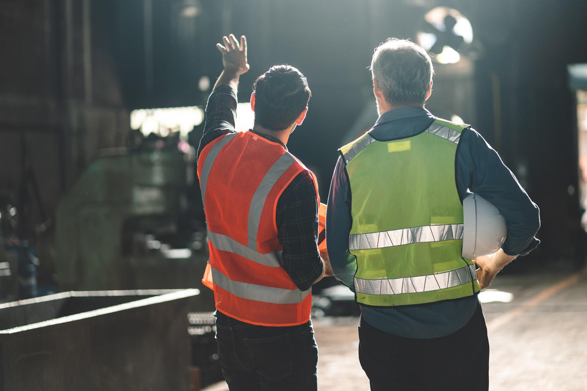 two manufacturing employees facing away at a plant