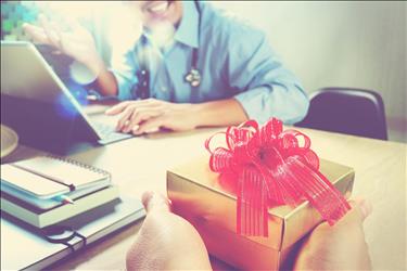 doctor at his desk receiving a gift from a coworker