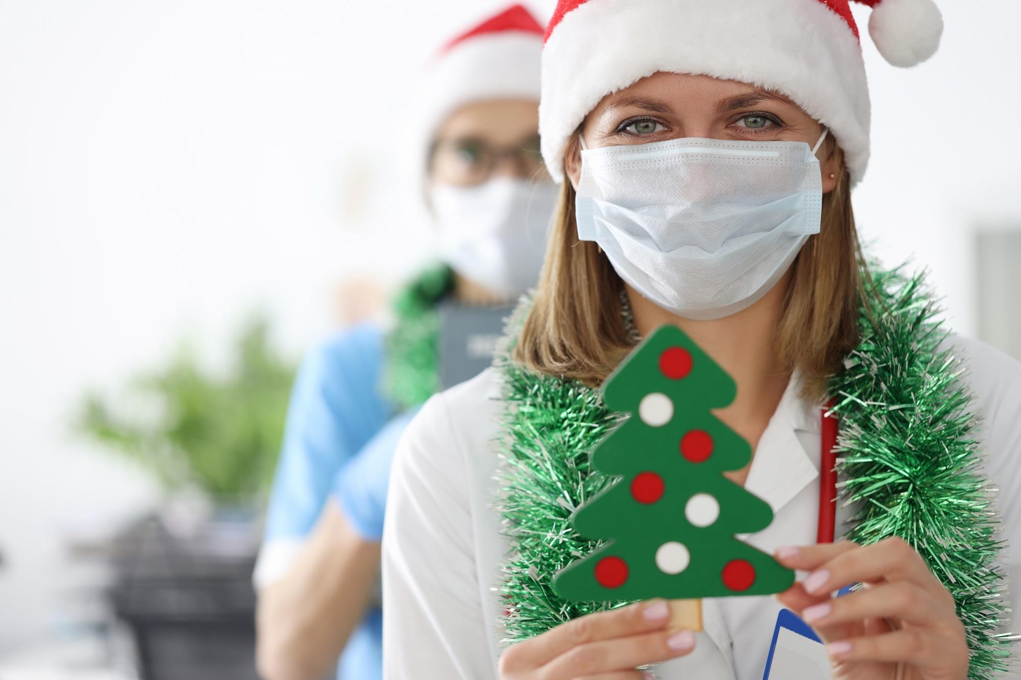 doctor in a santa claus hat holding a christmas tree craft