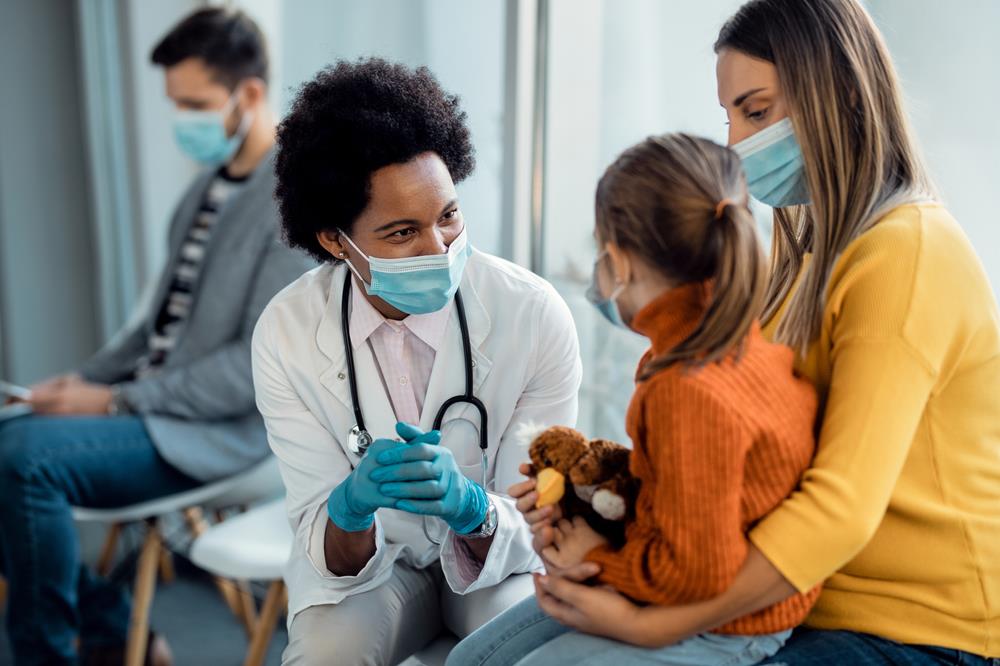 doctor sitting with a young patient and her mother