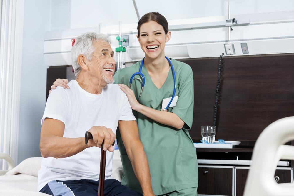 smiling nursing assistant and patient together in a hospital room