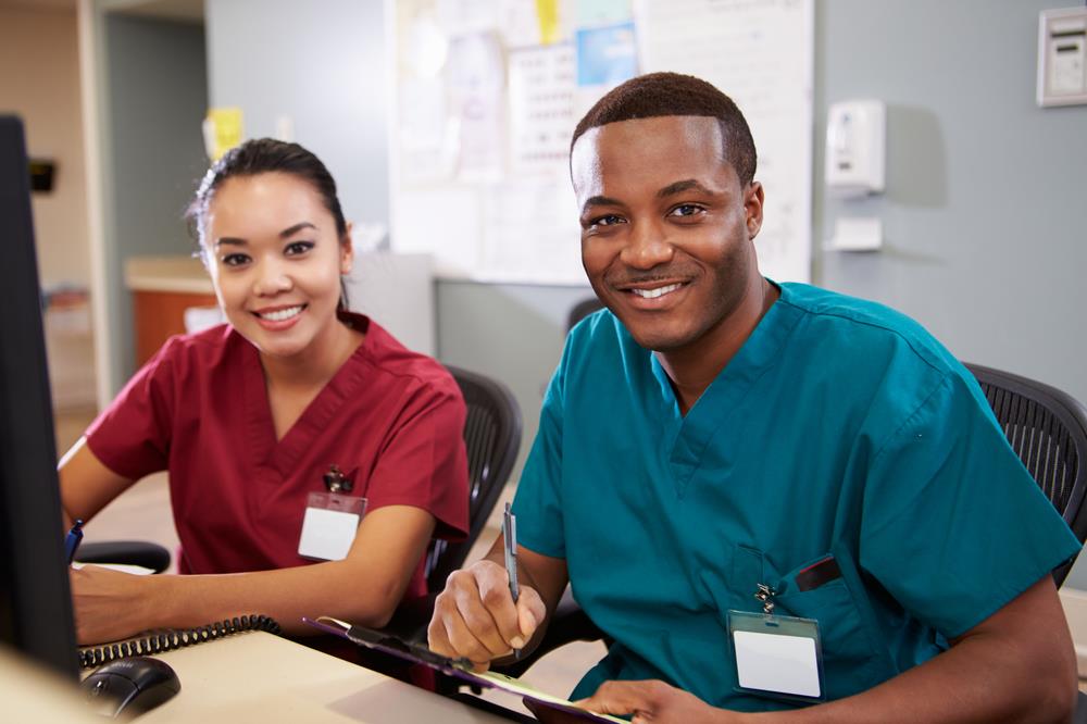 two nursing assistants working together at a computer station