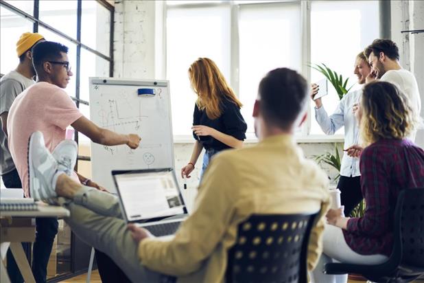 group of millennial employees meeting with a whiteboard