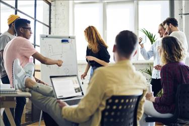 group of millennial employees meeting with a whiteboard