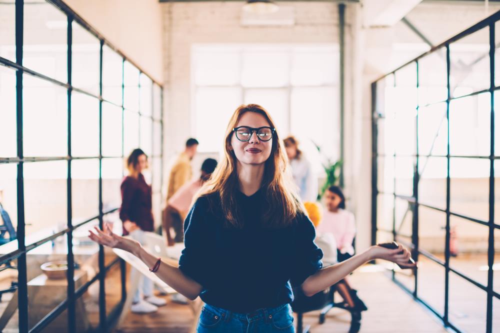 millennial worker in a conference room happily meditating