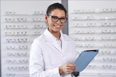 female optometrist at work in front of a display of glasses