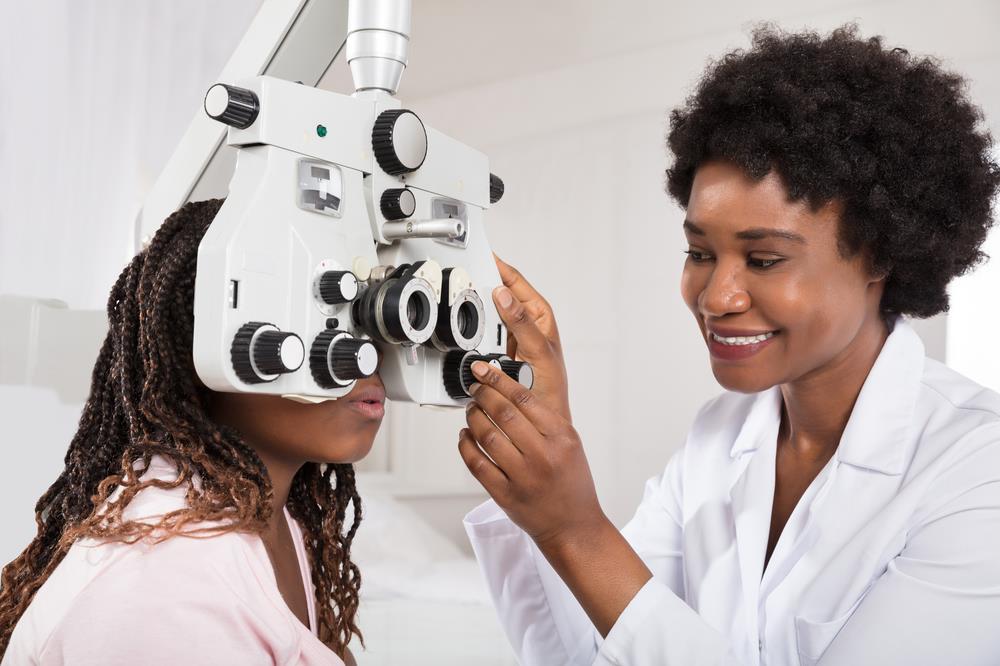 female optometrist completing an eye exam on an adult patient