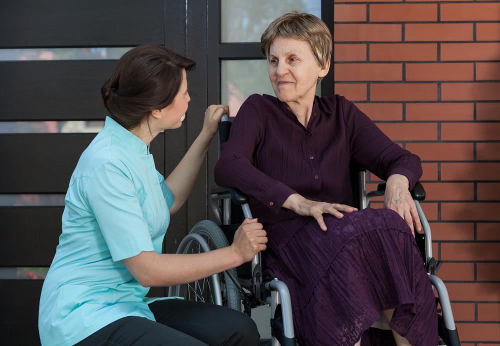 volunteer nurse assisting an elderly patient outside of a medical facility