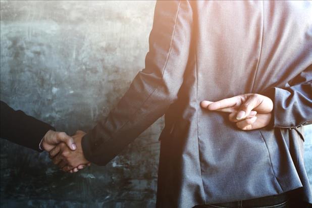 Businessman shaking someone's hand while crossing his fingers behind his back