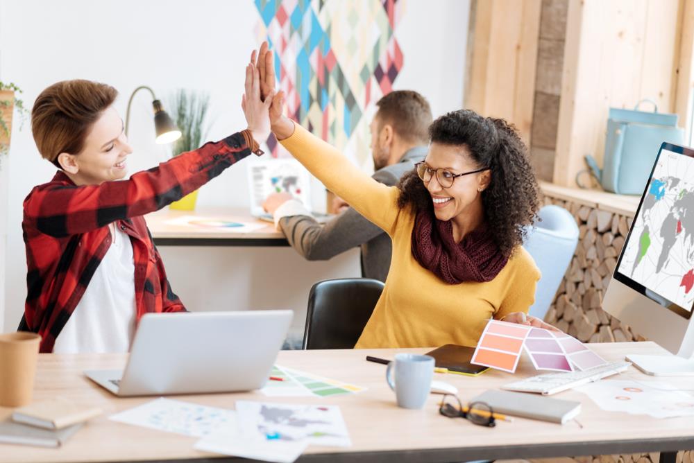 two happy employees high-fiving at work