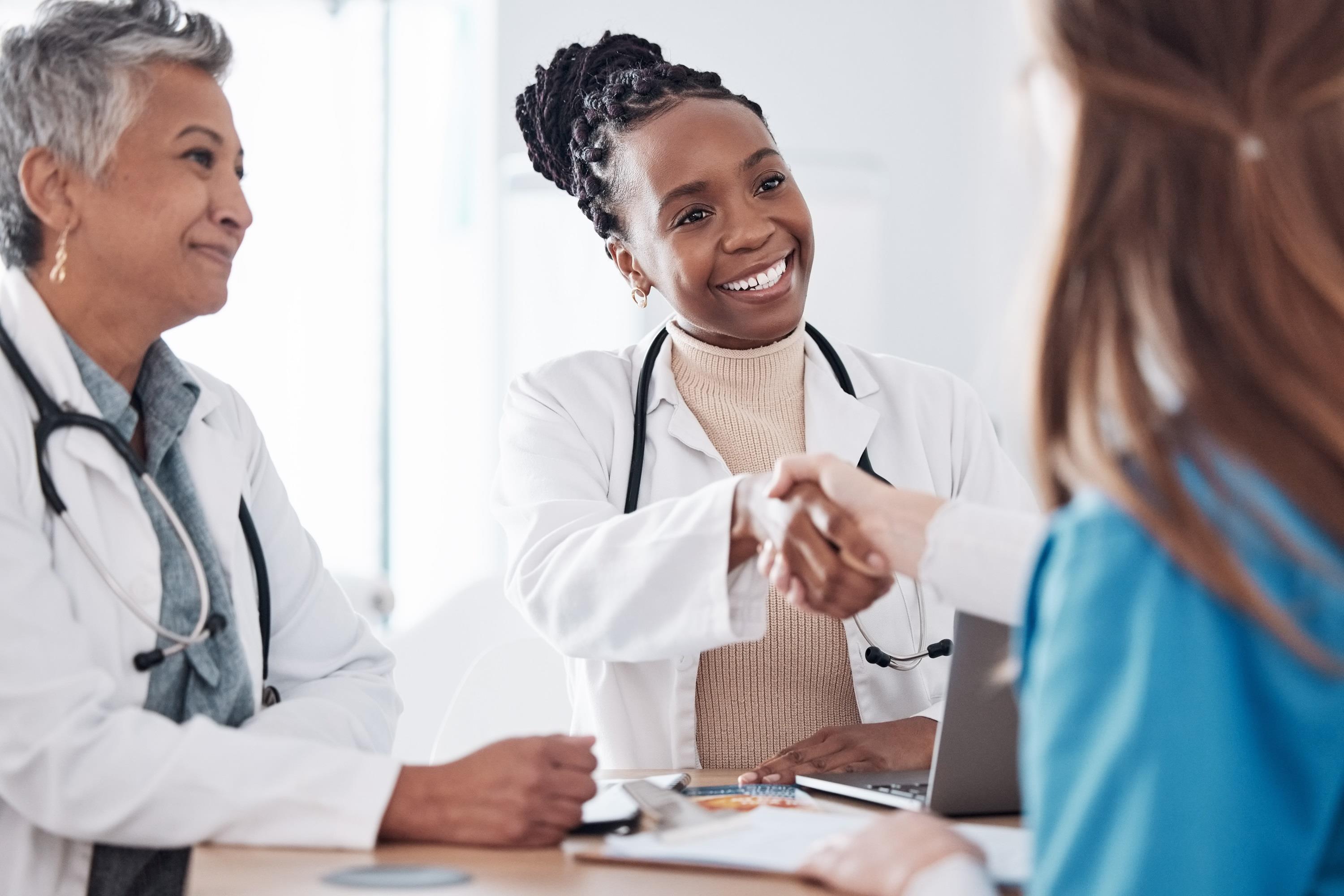 two medical professionals shaking hands during a meeting