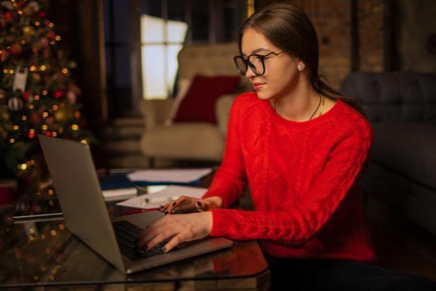 woman on computer with christmas tree in background